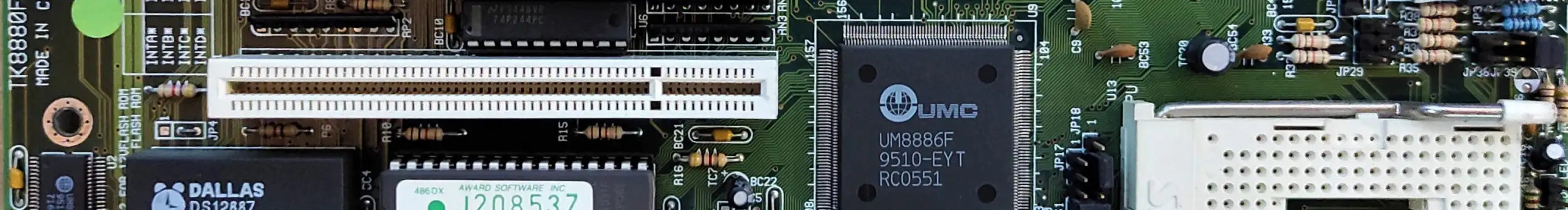 Black and silver computer motherboard with integrated circuit chips, ram slots, and various connectors.